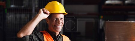 cheerful middle aged warehouse worker in hard hat and safety vest, professional headshot banner