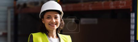 Photo for Banner of professional woman in safety vest and hard hat standing with hands in pockets in warehouse - Royalty Free Image