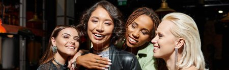 Téléchargez les photos : Excité et dynamique multiculturelles amies embrasser dans le bar pendant la fête, bannière horizontale - en image libre de droit