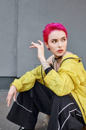 appealing tattooed woman with pink short hair posing in trendy urban outfit, fashion concept