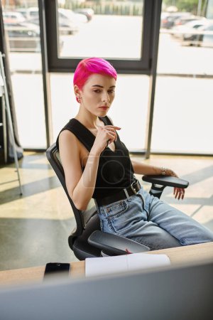 pensive young pink haired woman sitting with pen in hands and working hard, business concept
