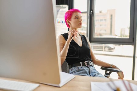 young pink haired woman in casual attire with tattoos sitting and looking away, business concept