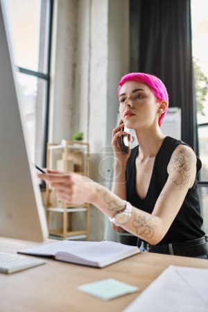 attractive pink haired woman in casual attire talking by phone while working hard, business concept