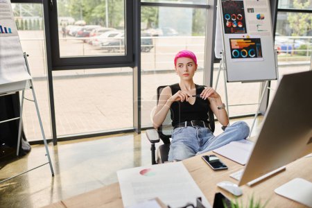 atractiva trabajadora con atuendo casual sentada con pluma mientras trabaja duro, concepto de negocio