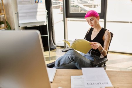 junge Arbeiterin in lässigem Outfit arbeitet hart mit Dokument mit dem Wort Konkurs auf dem Schreibtisch