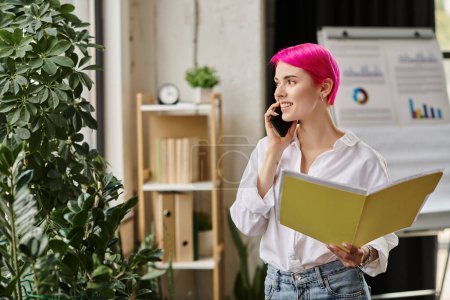 Téléchargez les photos : Joyeuse femme d'affaires aux cheveux roses tenant ses notes et détournant les yeux tout en parlant par téléphone - en image libre de droit