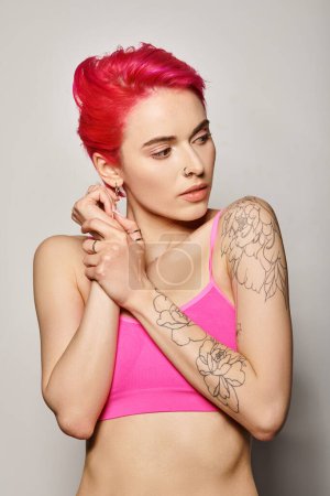 Photo for Portrait of beautiful young woman with pink hair posing and looking away on grey backdrop, vibrant - Royalty Free Image