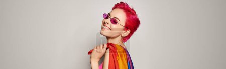 Photo for Young pleased female activist with pink hair and sunglasses posing with lgbt rainbow flag, banner - Royalty Free Image