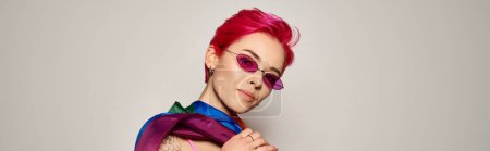 young woman with pink hair and stylish sunglasses posing with lgbt rainbow flag on grey, banner