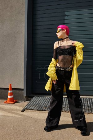 mujer joven de pelo rosa en gafas de sol y traje de moda posando al aire libre, moda de estilo callejero
