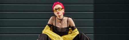 young woman with pink hair and tattoo posing in yellow sunglasses and stylish attire, banner