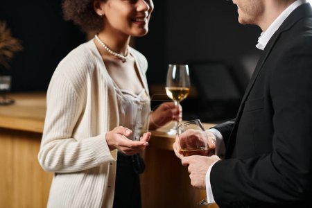 Ausgeschnittene Ansicht eines multikulturellen Paares im Abendkleid, das Weingläser hält und über Date spricht