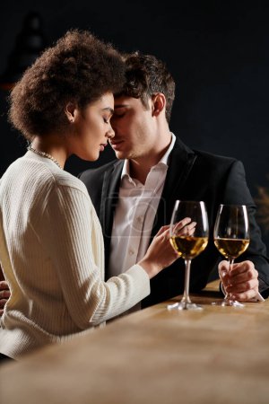 young interracial couple spending great time near glasses of wine during date on Valentines Day