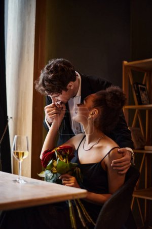 Gentleman küsst Hand einer afrikanisch-amerikanischen Frau mit Rosen beim Date am Valentinstag
