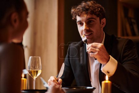 schöner Mann, der am Valentinstag das Abendessen genießt und seine Freundin anschaut, intime Umgebung
