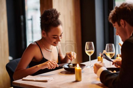 Photo for Happy african american woman enjoying meal next to boyfriend during date on Valentines day - Royalty Free Image