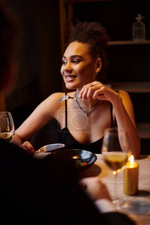 Photo for Joyful african american woman eating salad during date with boyfriend in restaurant, Valentines day - Royalty Free Image