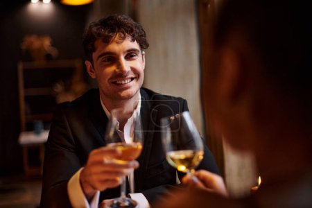 glücklich schöner Mann lächelt und schaut Freundin beim Date am Valentinstag an, romantisches Abendessen