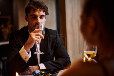 schöner Mann trinkt Weißwein in der Nähe Freundin beim Date am Valentinstag, romantisches Abendessen