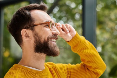 Téléchargez les photos : Joyeux beau architecte avec des lunettes en col roulé jaune posant dans son bureau pendant le travail - en image libre de droit