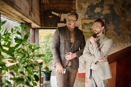 Téléchargez les photos : Beaux chefs d'entreprise concentrés dans des vêtements sophistiqués travailler ensemble et discuter démarrage - en image libre de droit