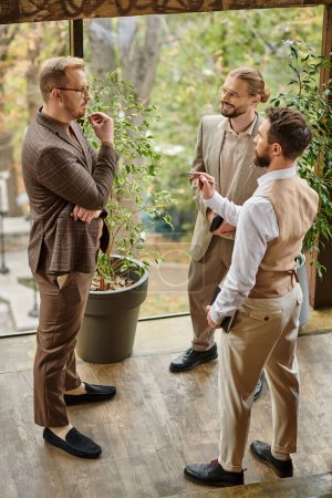 felices líderes de negocios guapos con gafas en elegantes atuendos elegantes discutiendo su startup