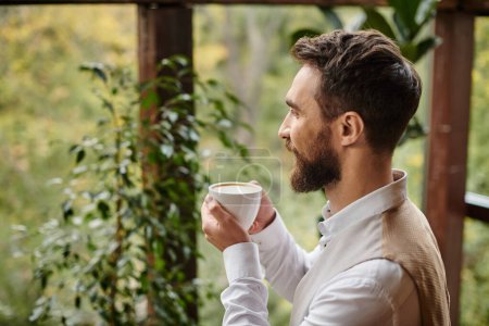 freudig attraktiver Geschäftsmann mit Bart und elegantem Stil, der seinen Kaffee trinkt