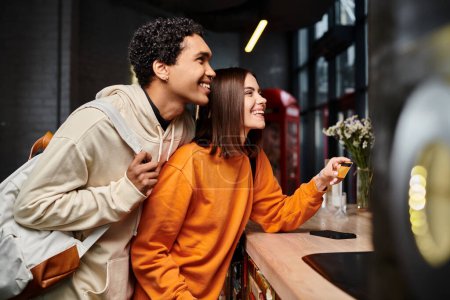 hombre afroamericano y mujer feliz celebración de la tarjeta de crédito en el mostrador de recepción en el albergue, viajes