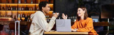 negro hombre y mujer riendo y hablando en una mesa de café, con su computadora portátil a su lado, bandera