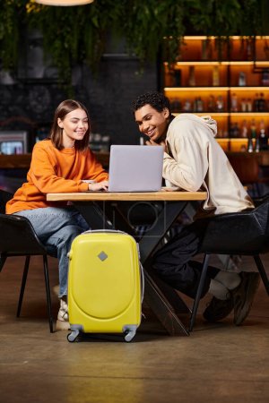 Schwarze Männer und Frauen schauen auf Laptop auf Cafétisch, ihr Gepäck neben sich, digitaler Nomade
