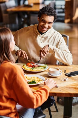 feliz pareja comparte un momento tranquilo juntos, ya que disfrutan de un almuerzo caliente en la comodidad de la acogedora cafetería