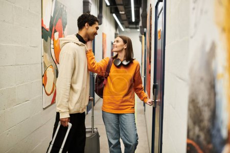 Young interracial couple smiling in hostel hallway, cheerful woman opening door to their room