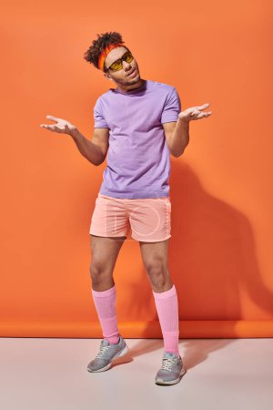Photo for Confused african american sportsman in sunglasses and gym attire gesturing on orange background - Royalty Free Image