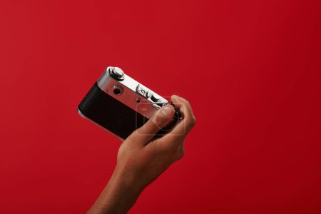 abgeschnittenes Foto eines afrikanisch-amerikanischen Fotografen, aufgenommen auf einer Retro-Kamera auf rotem Hintergrund