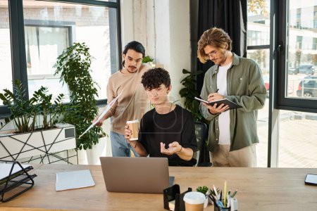 jóvenes emprendedores lluvia de ideas sobre un ordenador portátil en una oficina moderna, tres hombres creando startup