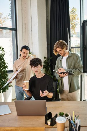 Foto de Jóvenes empresarios lluvia de ideas sobre un ordenador portátil en una oficina moderna, tres hombres creando startup - Imagen libre de derechos