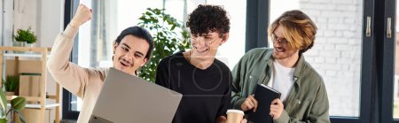 Three young men engaged in a lively discussion over a laptop at a coworking space, success banner