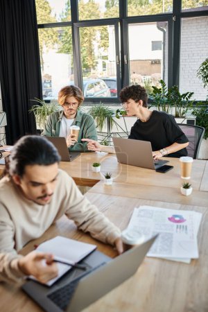 Photo for Young professionals sharing ideas near laptops in a coworking space, blurred foreground - Royalty Free Image