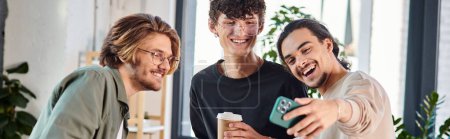 Young businessmen enjoying a coffee break and taking a selfie in a coworking space, banner