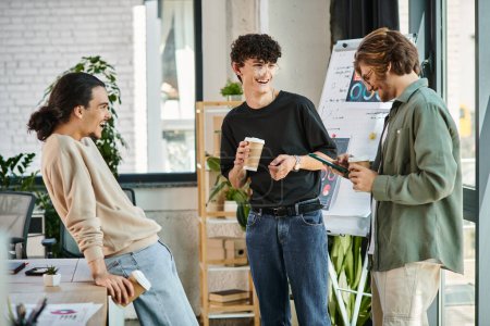 young coworkers in their 20s sharing ideas and laughing over coffee in modern office, startup team