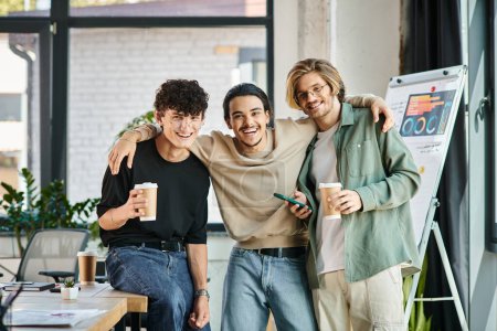 Téléchargez les photos : Jeunes hommes ambitieux, trois collègues masculins joyeux collant autour d'un café dans un bureau créatif - en image libre de droit