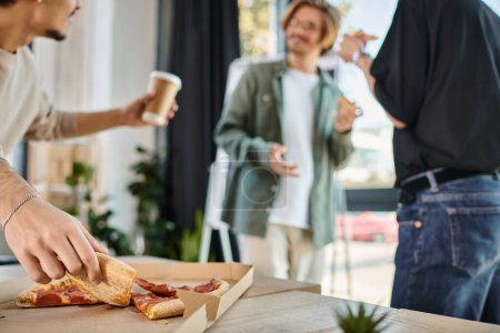 Photo for Focus on team member with coffee taking slice of pizza in friendly office atmosphere, lunch break - Royalty Free Image