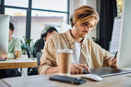 Hombre enfocado que trabaja en un proyecto creativo y usa su tableta en un equipo de coworking y retoque de startups