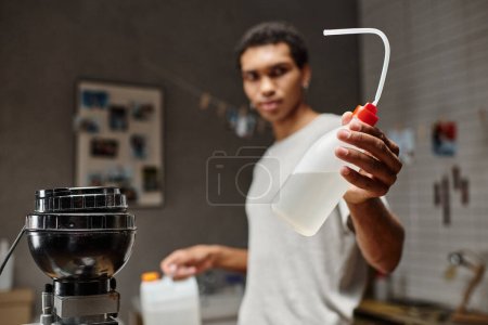 Photo for Focused dark skinned photographer prepares chemicals for film development in a modern darkroom - Royalty Free Image