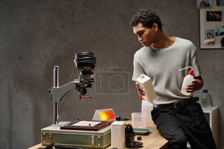 A focused african american man carefully measuring photo chemicals in a well-organized darkroom