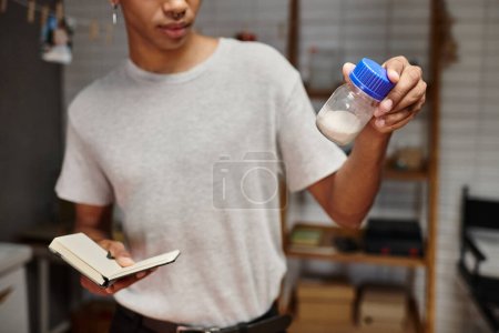 Photo for Cropped african american photographer examines film developing powder and holding notebook - Royalty Free Image