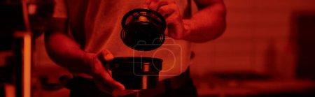 Photo for Cropped banner of photographer holding film canister and developing photos in red darkroom - Royalty Free Image