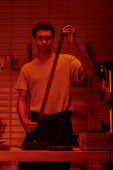 focused african american guy unwinds film in preparation for development in darkroom with red light Sweatshirt #692601044