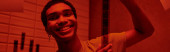 cheerful african american man hanging freshly developed film strip  in a red-lit darkroom, banner Longsleeve T-shirt #692601340