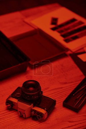 Téléchargez les photos : Une table de chambre noire avec caméra analogique et des outils pour le développement de films sous la lumière rouge - en image libre de droit
